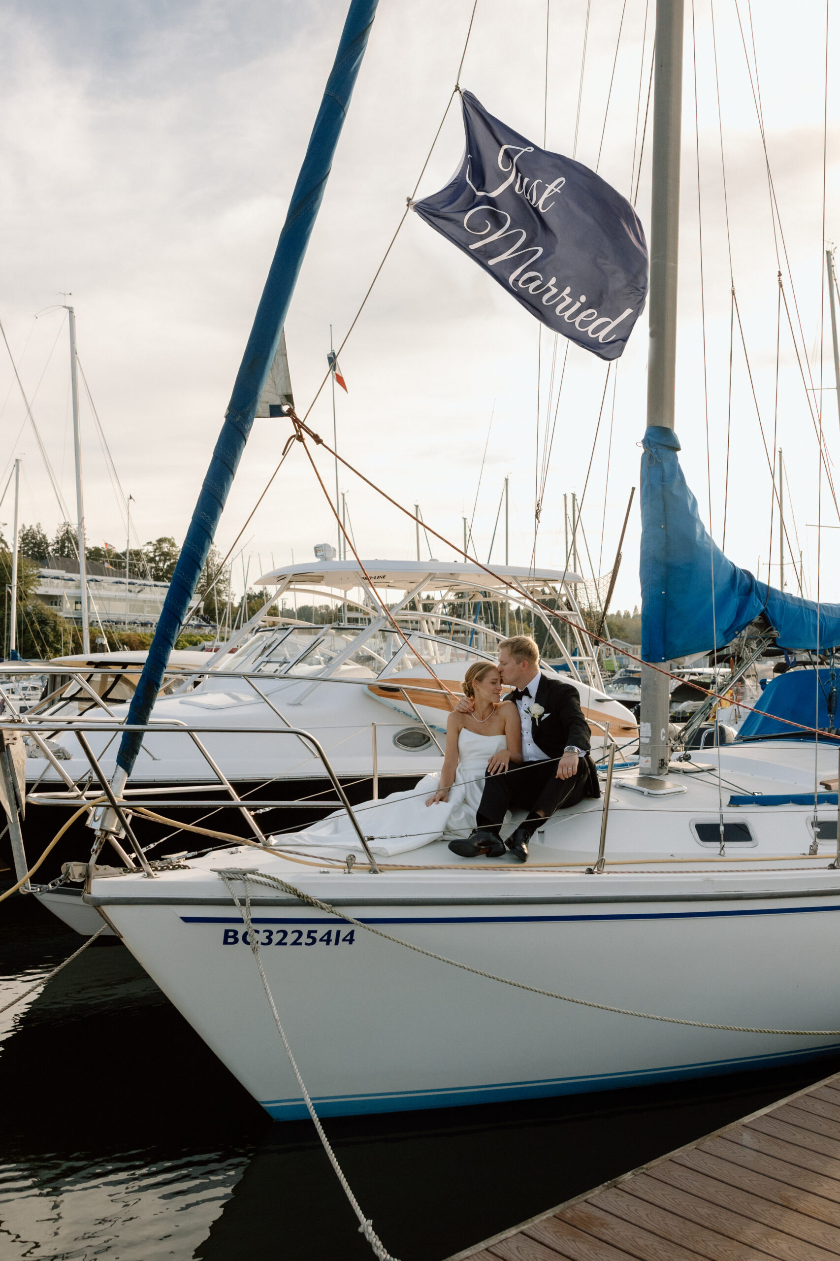 couple sitting on a sail boat with a just married sign blowing in the wind above them