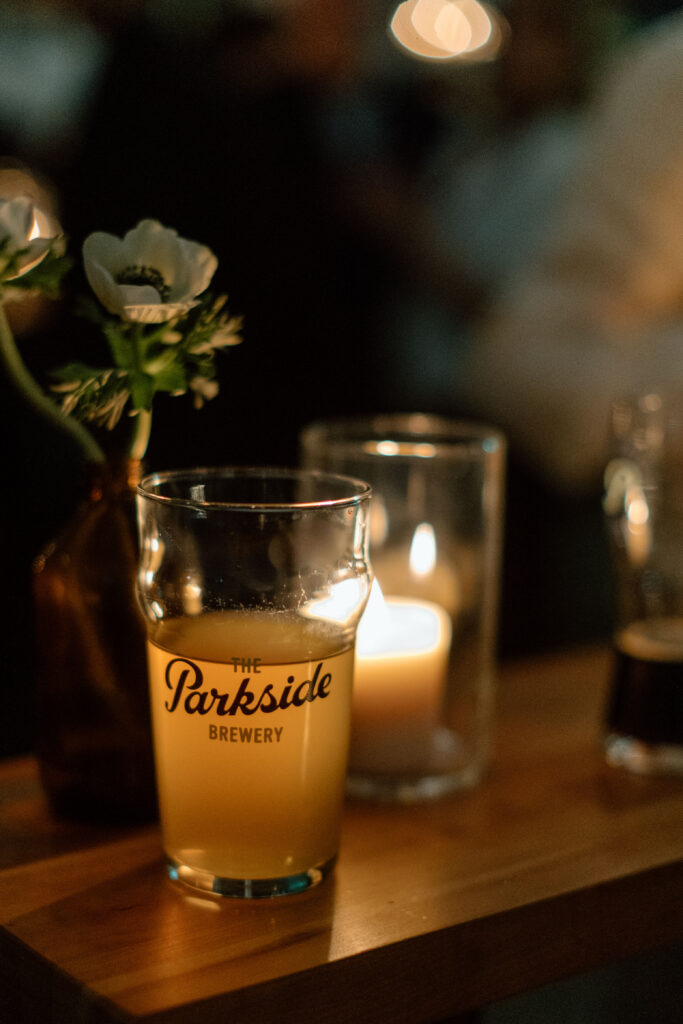 Beer glass at night illuminated by a candle at a Parkside Brewery wedding reception