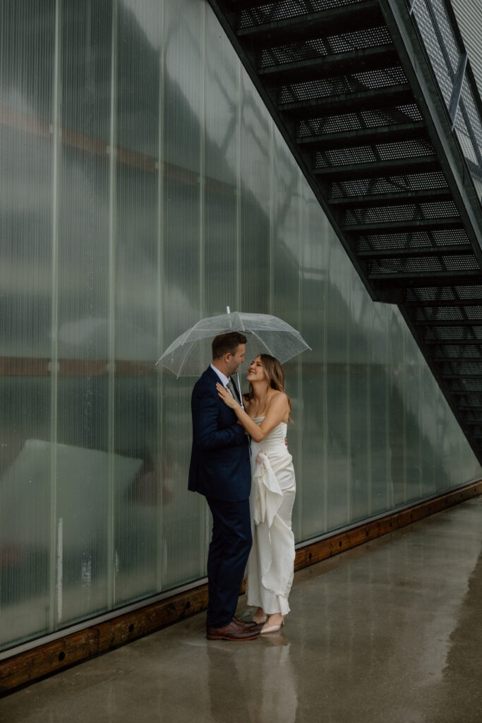 A couple huddled in under an umbrella on the dock at UBC Boathouse